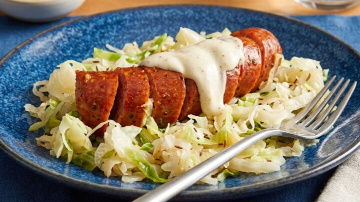 Looking for a quick, comforting dinner packed with deep, savory flavor? This classic pairing features juicy pan-seared smoked sausage layered over a hearty bed of tangy, tender braised cabbage. #SausageRecipes #ComfortFood #EasyDinner #MealPrep #WeeknightMeals #RusticCooking