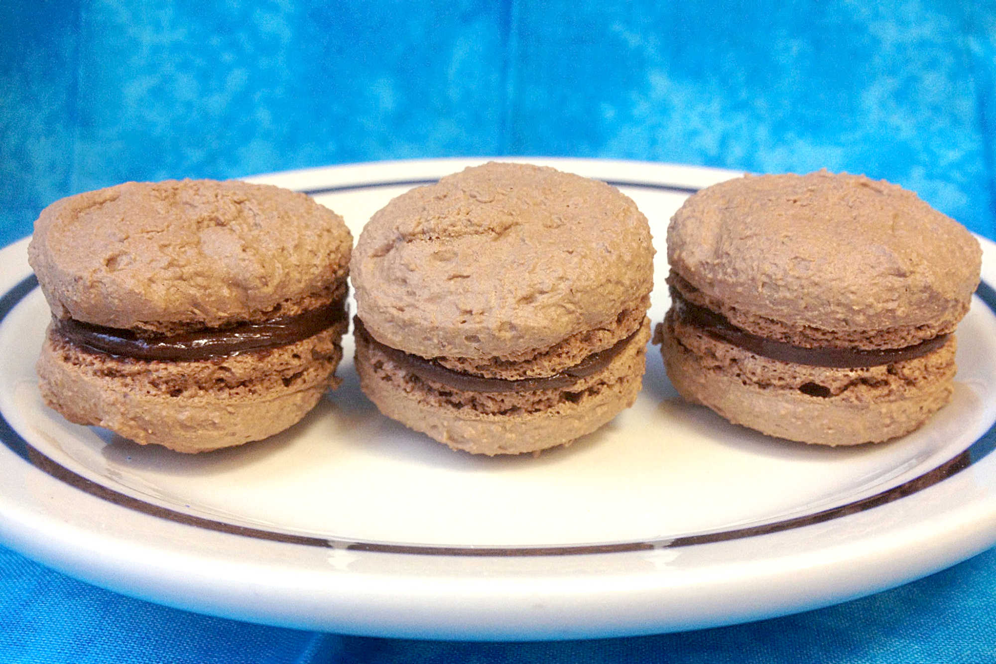 Hazelnut Chocolate Macarons are the perfect blend of nutty and chocolaty goodness. You won't be disappointed with this made for each other combo. #MacaronMania #ChocolateCravings #SweetTreats #HazelnutObsession #FrenchPastryPerfection