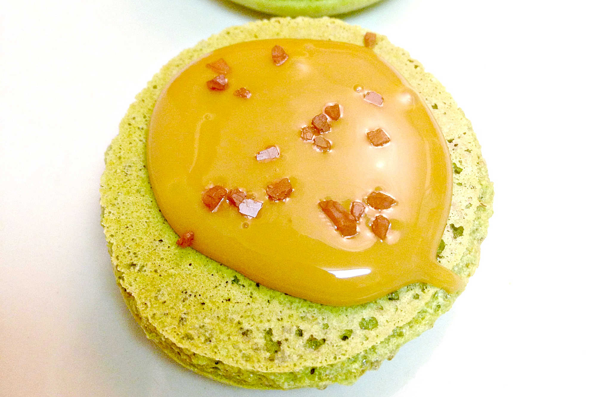 Rich pistachios pair with creamy, salted caramel in these irresistible Pistachio and Salted Caramel Macaron. #MacaronMondays #PistachioPerfection #SaltedCaramelCravings #FrenchPastryLove #DeliciousDupes
