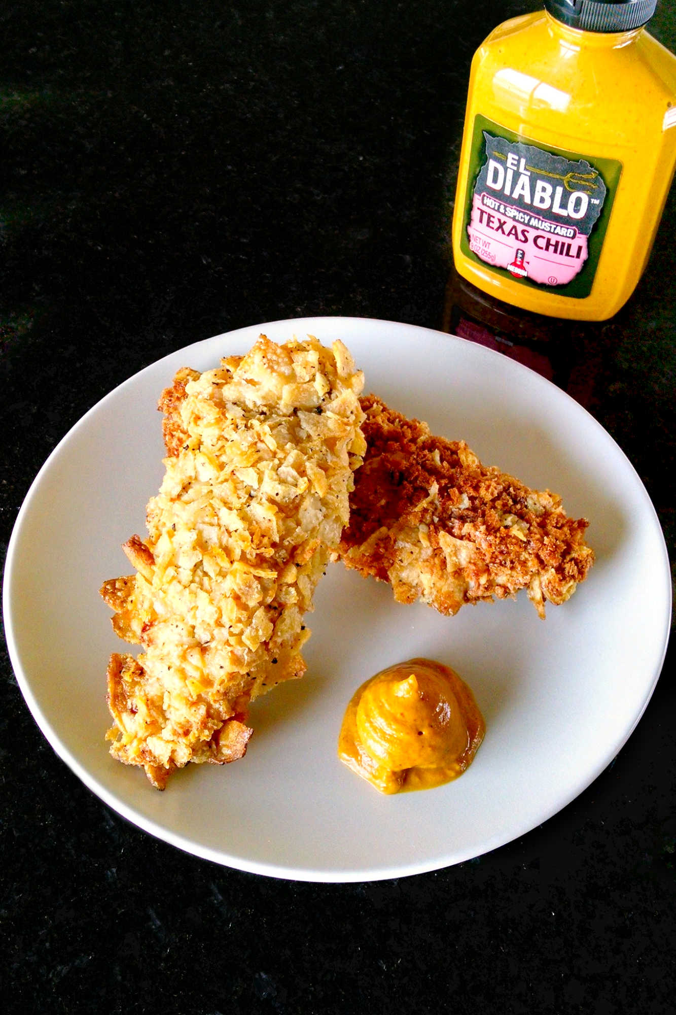 Spice up your chicken game with these oven-fried potato chip chicken tenders! With a crispy potato chip coating and juicy chicken inside, this dish is sure to be a crowd-pleaser. Try them out for your next game day or movie night.  #ovenfriedchicken #potatochipchicken #easyrecipes #crispychicken #homecookingmadetasty