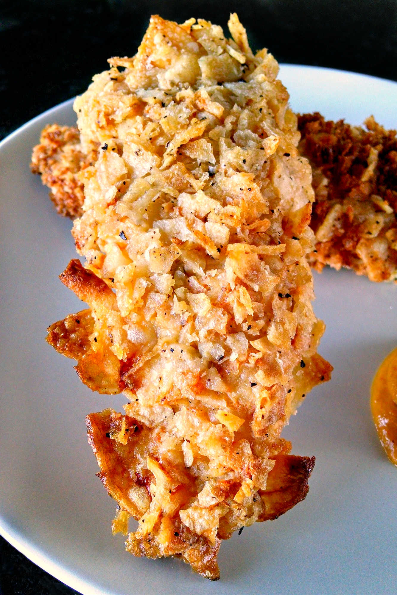 Spice up your chicken game with these oven-fried potato chip chicken tenders! With a crispy potato chip coating and juicy chicken inside, this dish is sure to be a crowd-pleaser. Try them out for your next game day or movie night.  #ovenfriedchicken #potatochipchicken #easyrecipes #crispychicken #homecookingmadetasty