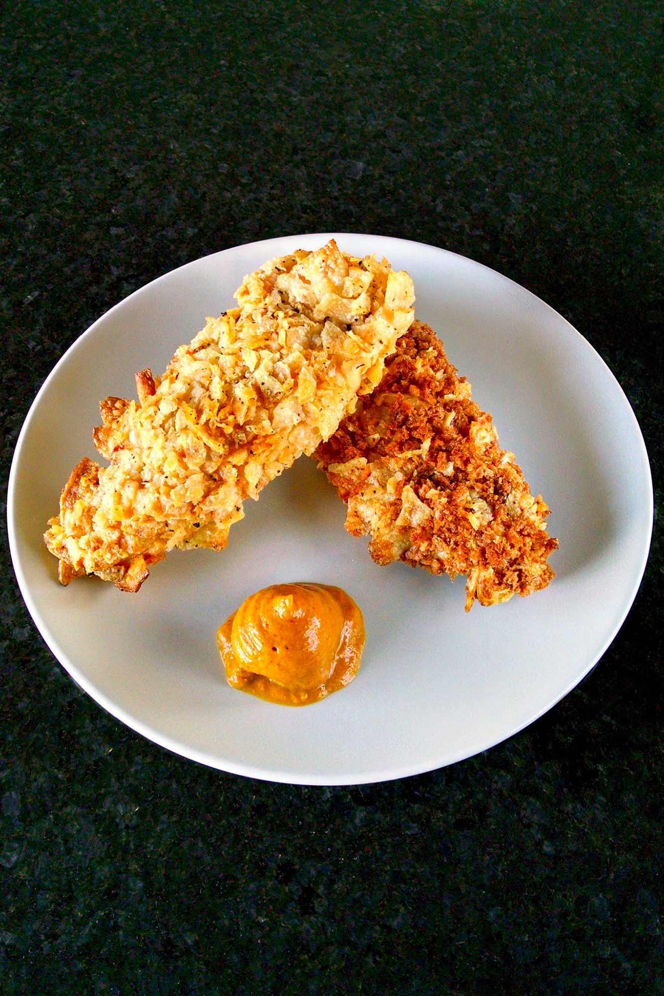 Spice up your chicken game with these oven-fried potato chip chicken tenders! With a crispy potato chip coating and juicy chicken inside, this dish is sure to be a crowd-pleaser. Try them out for your next game day or movie night.  #ovenfriedchicken #potatochipchicken #easyrecipes #crispychicken #homecookingmadetasty