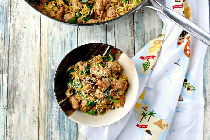 One Pot Italian Sausage Orzo with Spinach and mushrooms garnished with Parmesan cheese and crushed red peppers.