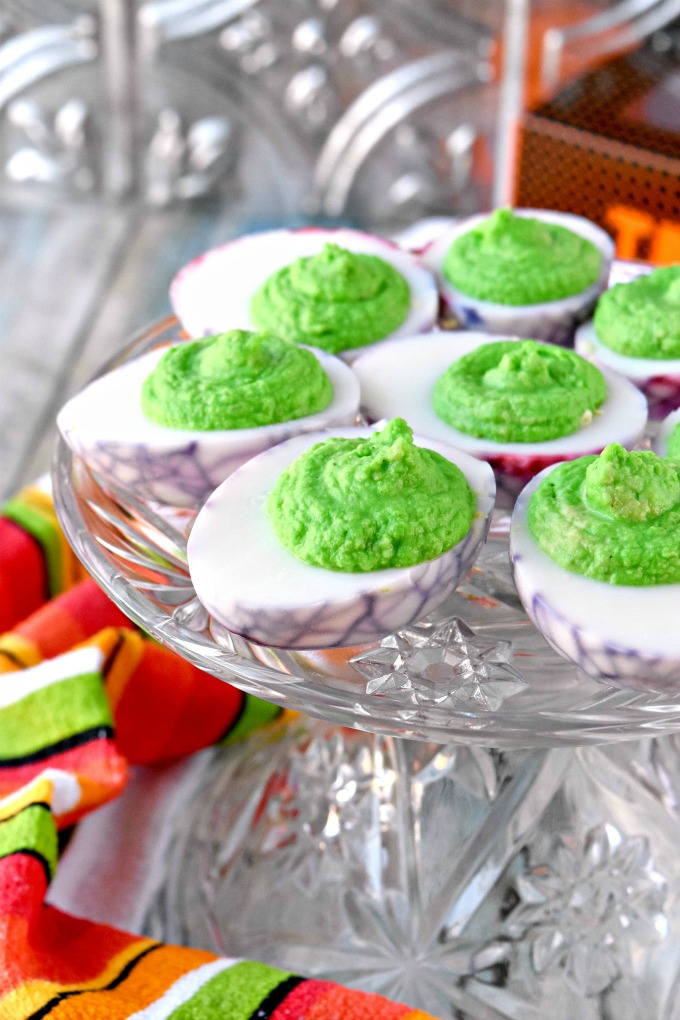 Simple deviled eggs are turned into a fun and delicious Halloween party appetizer.  Dragons Eggs are avocado deviled eggs with a kick of garlic making them creamy with a spicy garlic kick.  #HalloweenTreatsWeek
