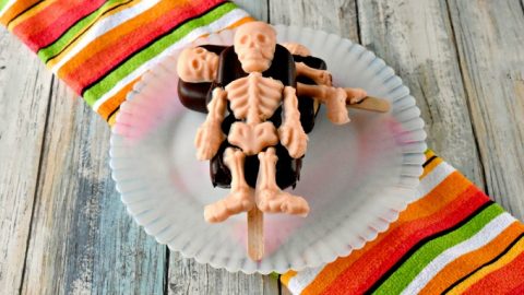 A simple popsicle recipe is turned into a Halloween treat with Wilton skeleton candy molds.  Skeleton Popsicles are chocolate coated pudding pops decorated with skeleton candy bits.  #HalloweenTreatsWeek