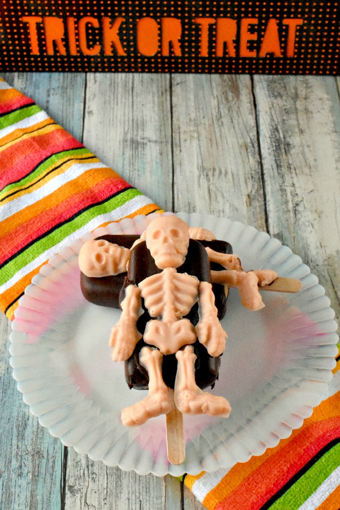 A simple popsicle recipe is turned into a Halloween treat with Wilton skeleton candy molds.  Skeleton Popsicles are chocolate coated pudding pops decorated with skeleton candy bits.  #HalloweenTreatsWeek