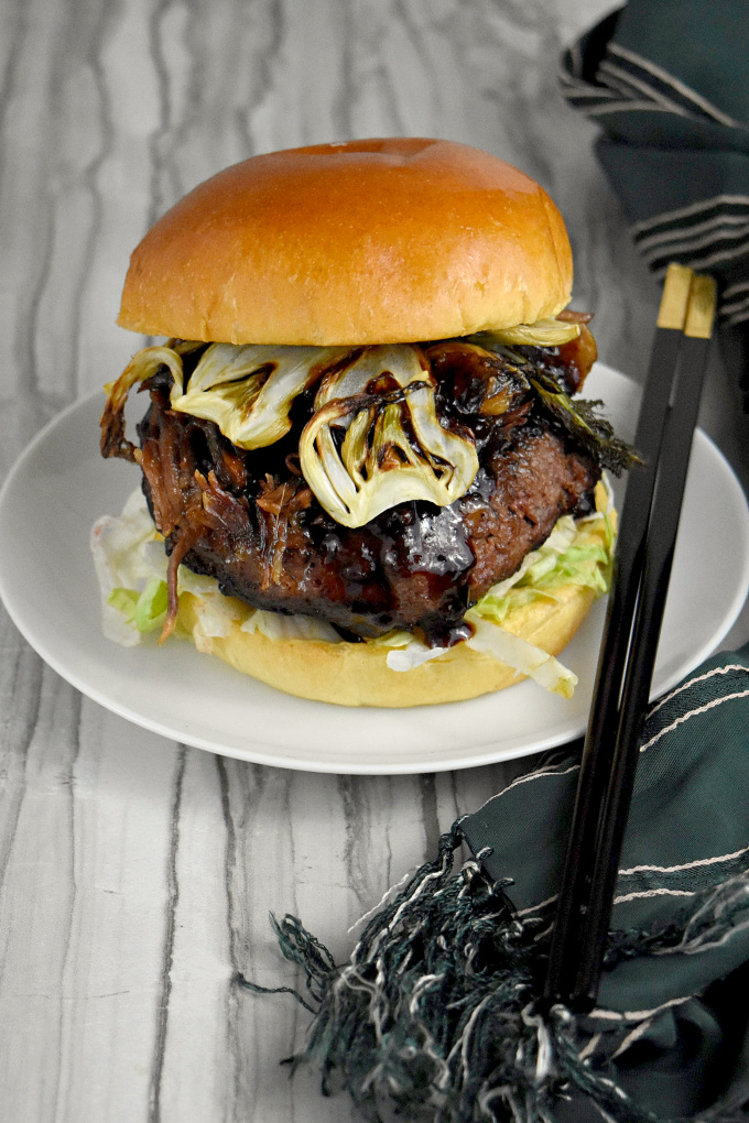 Asian Inspired Short Rib Burger has soy, ginger, sesame oil, and hoisin sauce. It's topped with braised short ribs marinated with lemongrass, garlic, ginger, and soy sauce and crispy fennel chips. It's packs mouthful after delicious mouthful of flavor.