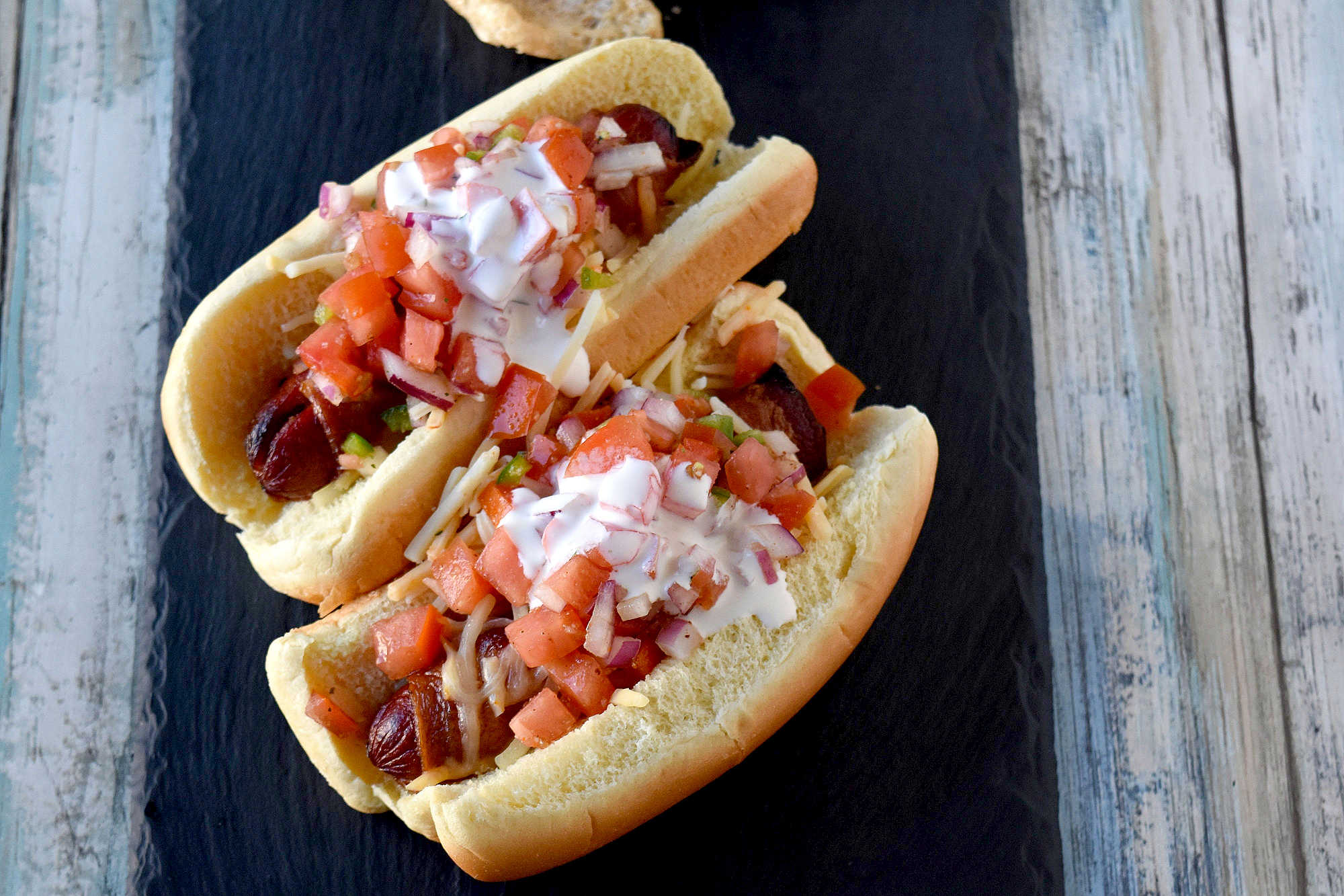 Air Fryer Bacon Wrapped Hot Dogs are simple to make and elevated with pico de gallo and crema toppings. The smoky and salty bacon complements the crisp and cool pico and rich crema. #OurFamilyTable