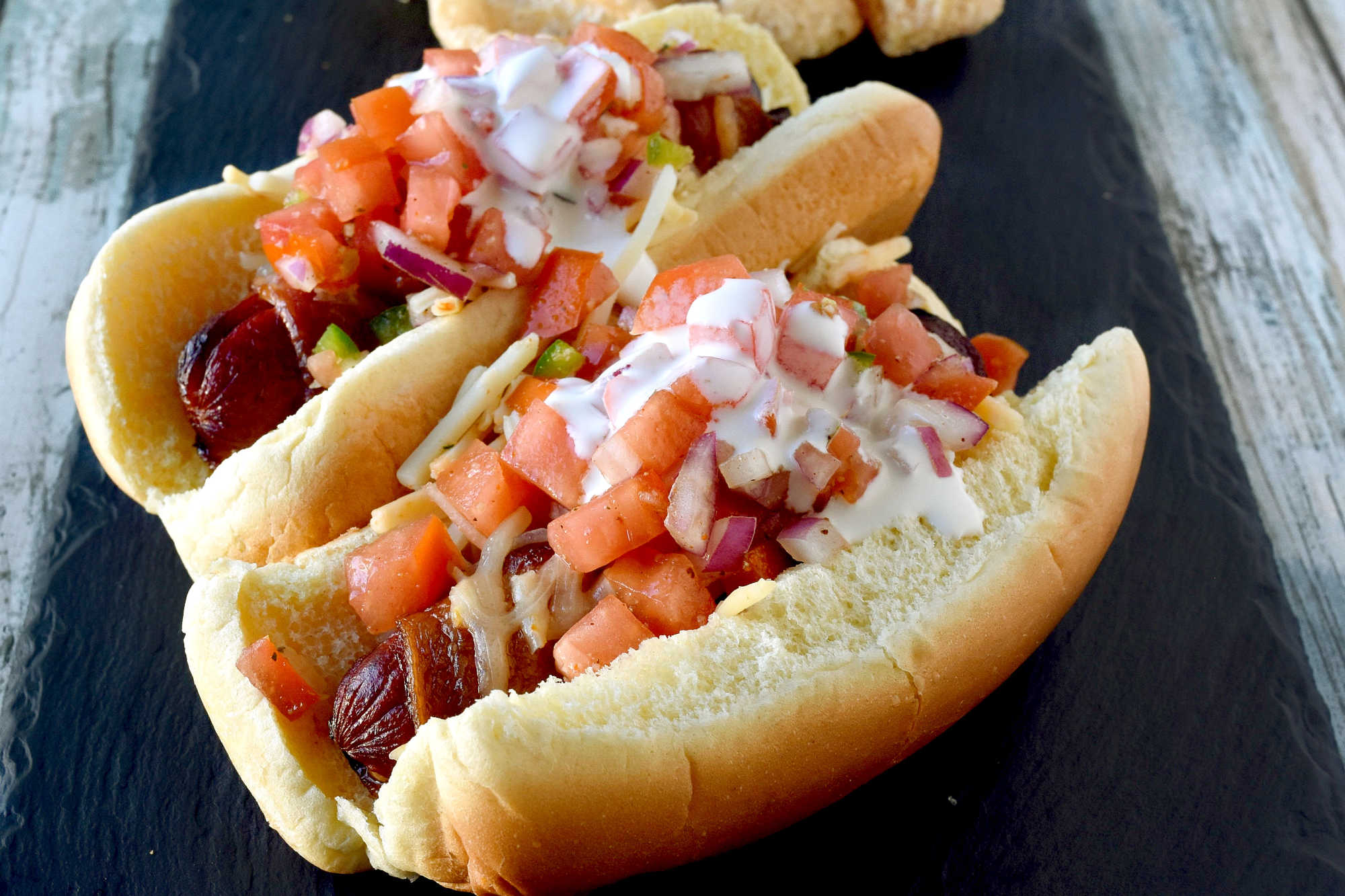 Air Fryer Bacon Wrapped Hot Dogs are simple to make and elevated with pico de gallo and crema toppings. The smoky and salty bacon complements the crisp and cool pico and rich crema. #OurFamilyTable