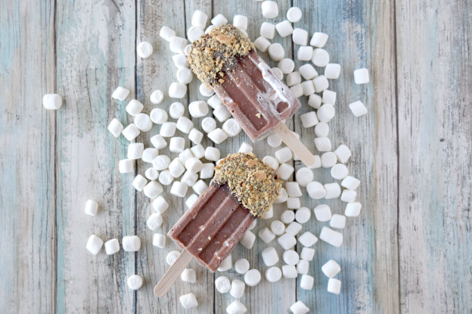 S’More’s Popsicles are full of chocolate fun with marshmallow fluff coated with more chocolate and graham cracker pieces.  They’re fun to make and oh so delicious for summer. #SummerDessertWeek