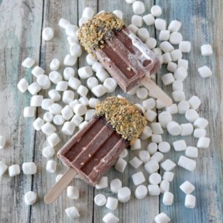 S’More’s Popsicles are full of chocolate fun with marshmallow fluff coated with more chocolate and graham cracker pieces. They’re fun to make and oh so delicious for summer. #SummerDessertWeek