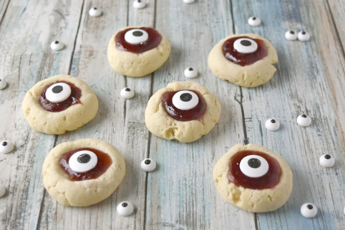 Turn a simple and easy thumbprint cookie into Eyeball Thumbprint Cookies!  Filled with cherry jam and topped with large candy eyes for a fun Halloween treat. #HalloweenTreatsWeek