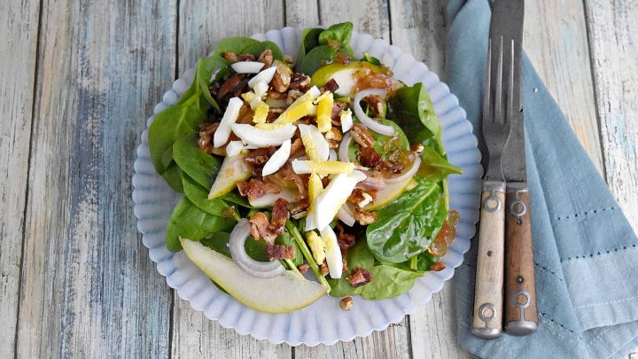 Sweet and tangy bacon dressing is drizzled over sweet pears, spinach, and sliced shallots. Top Wilted Pear and Shallot Salad with chopped pecans and sliced hard-boiled eggs for a hearty and delicious salad. #wiltedsalad #spinachsalad #pearsalad #bacondressing #WiltedSaladSensation #PearShallotEats #FarmtoTableFaves #HealthyGreensInspo #BlissfulBitesByUs