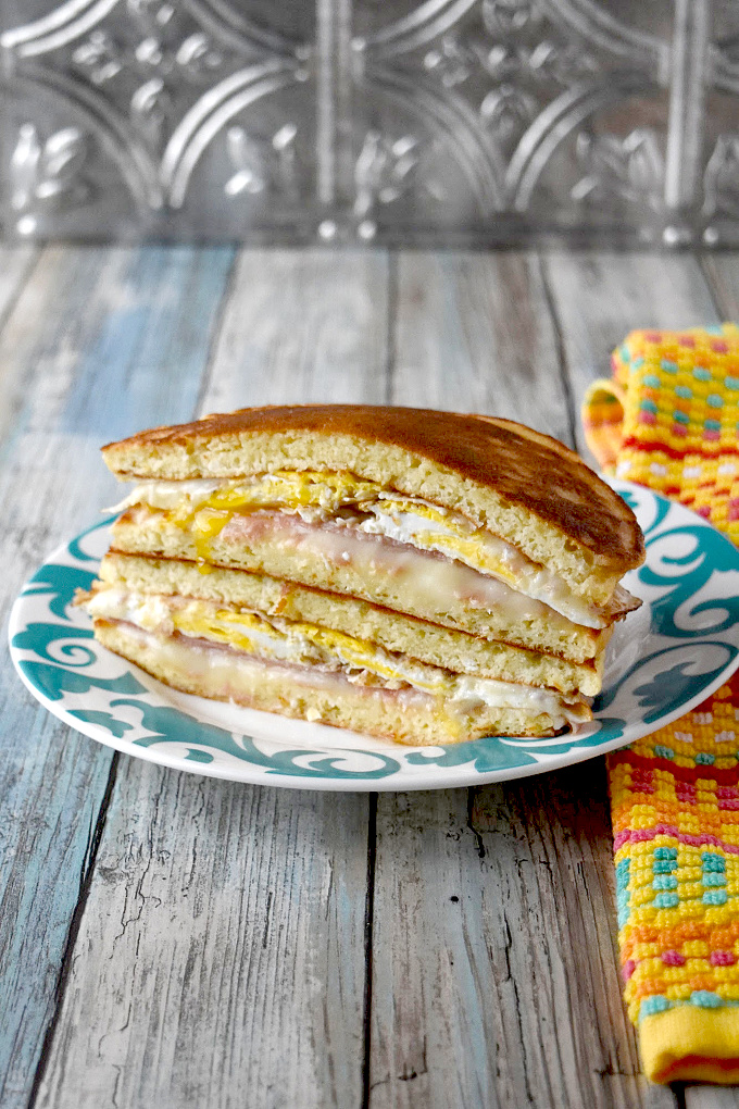 Breakfast Pancake Grilled Cheese skips traditional bread or buns and uses pancakes to hold the fried egg, cheese, and ham together.  It's a fun and delicious breakfast sandwich you can easily make ahead. #OurFamilyTable