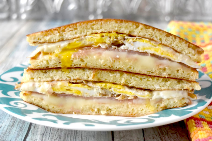 Breakfast Pancake Grilled Cheese skips traditional bread or buns and uses pancakes to hold the fried egg, cheese, and ham together.  It's a fun and delicious breakfast sandwich you can easily make ahead. #OurFamilyTable