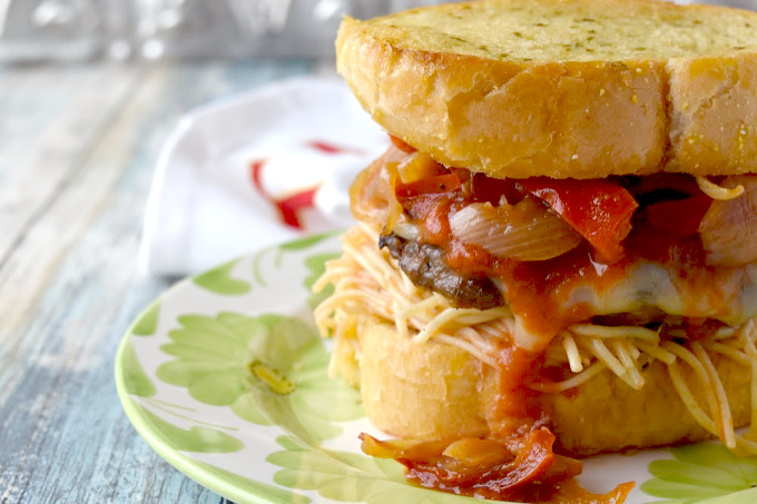 Italian sausage and ground pork come together in this Italian Sausage Parmesan Burger. It's packed with Italian flavors, topped with cheese, and sits on top of spaghetti and Texas toast garlic bread. #BurgerMonth