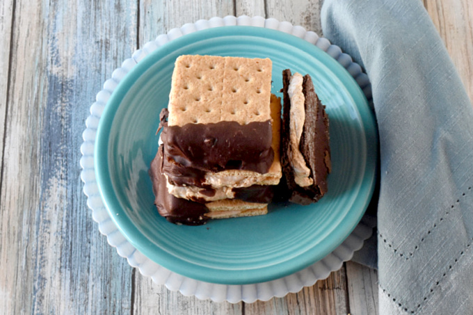 Fluffernutter Bites are a cross between a s'more and a fluffernutter sandwich.  Marshallow fluff and peanut butter are sandwiched between graham crackers and dipped in chocolate. #BacktoSchoolTreats