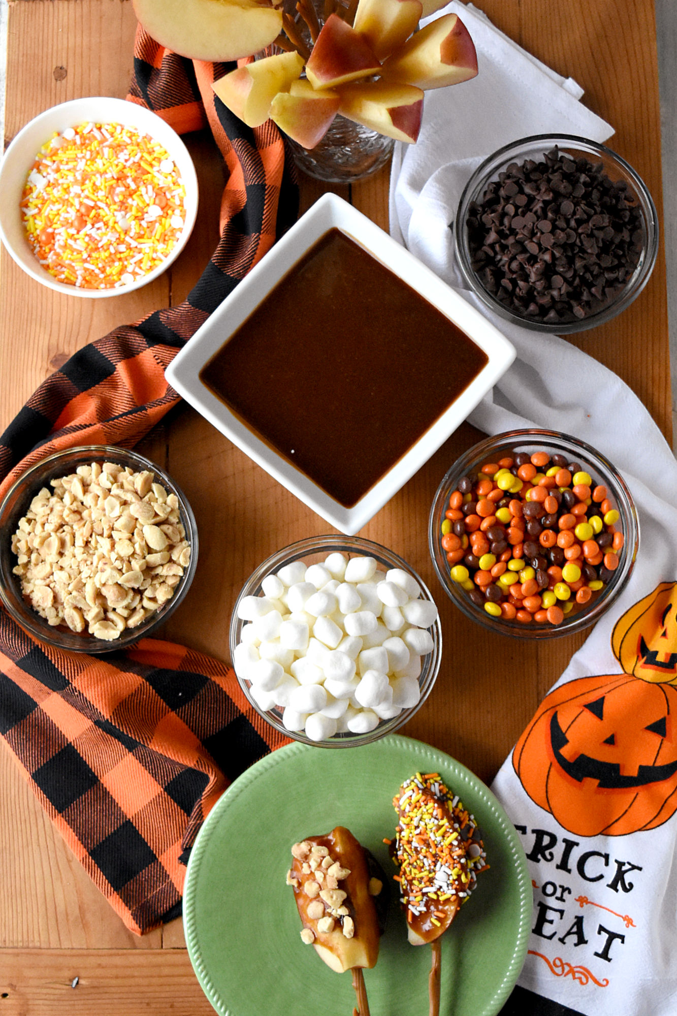 Caramel Apple Board is packed with fun toppings and a delicious peanut butter caramel.  Made with brown sugar, the caramel sauce is simple to make and tastes delicious. #HalloweenTreatsWeek