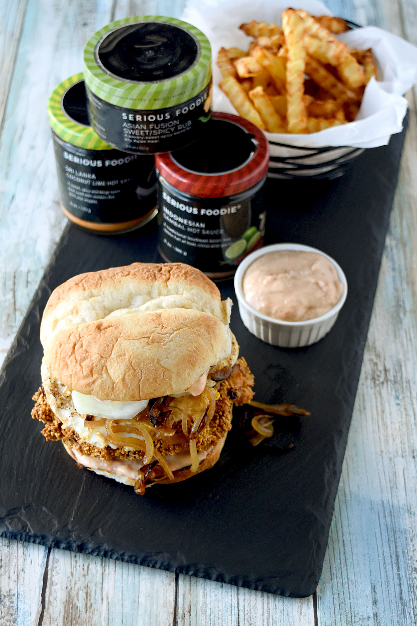 Crispy Nasi Lemak Chicken Sandwich has so much flavor! It has a coconut lime marinated chicken thigh coated in corn cereal topped with caramelized onions, crispy cucumber, a fried egg, and delicious sambal fry sauce.  #SeriousFoodieRecipeChallenge #SeriousFoodie #BitesAroundTheWorld