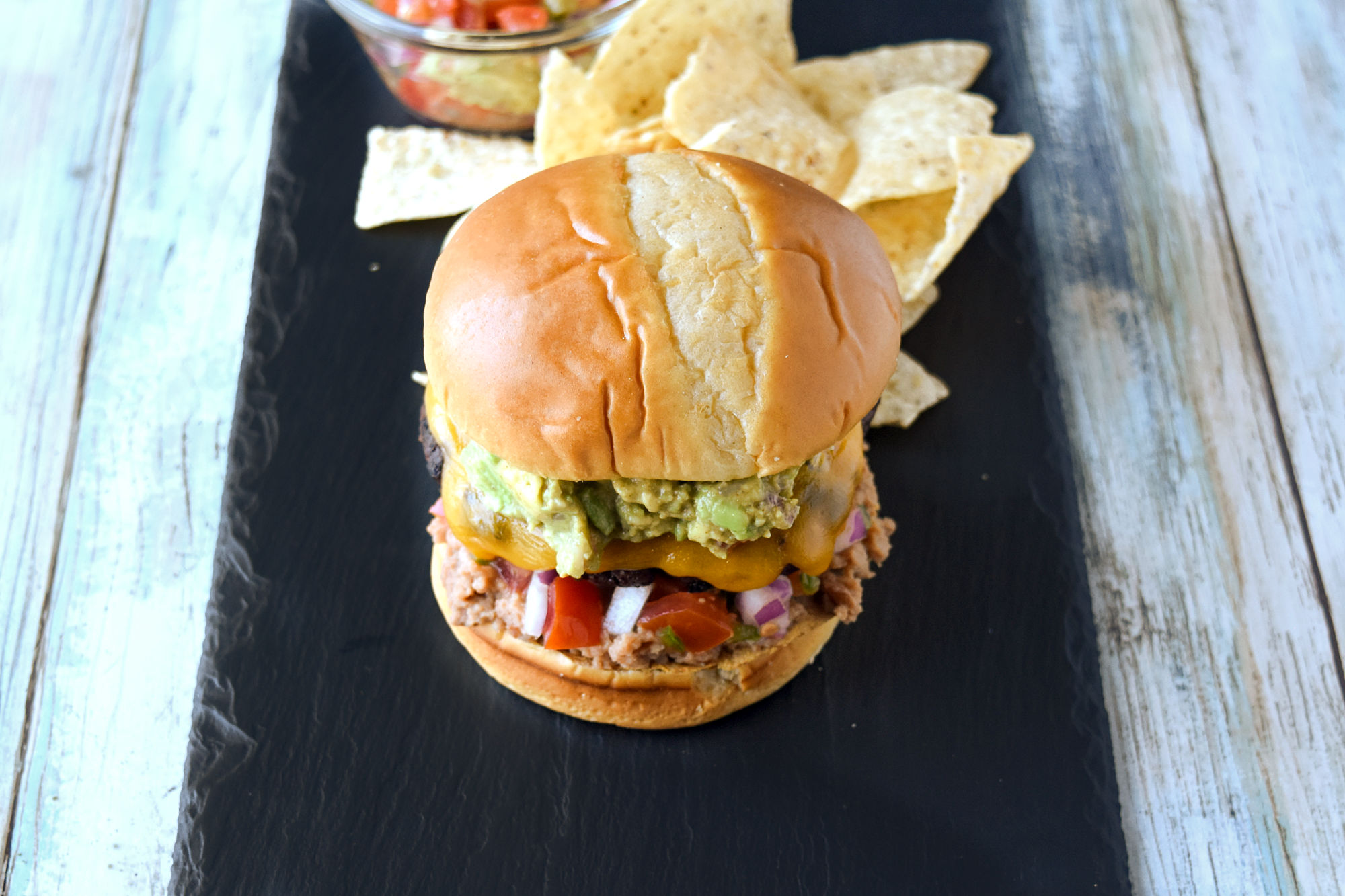 The Chalupa Burger layers a taco seasoned burger with a tostada, pico de gallo, Cheddar cheese, and guacamole.  It’s the ultimate in Latin inspired hamburgers. #BurgerMonth