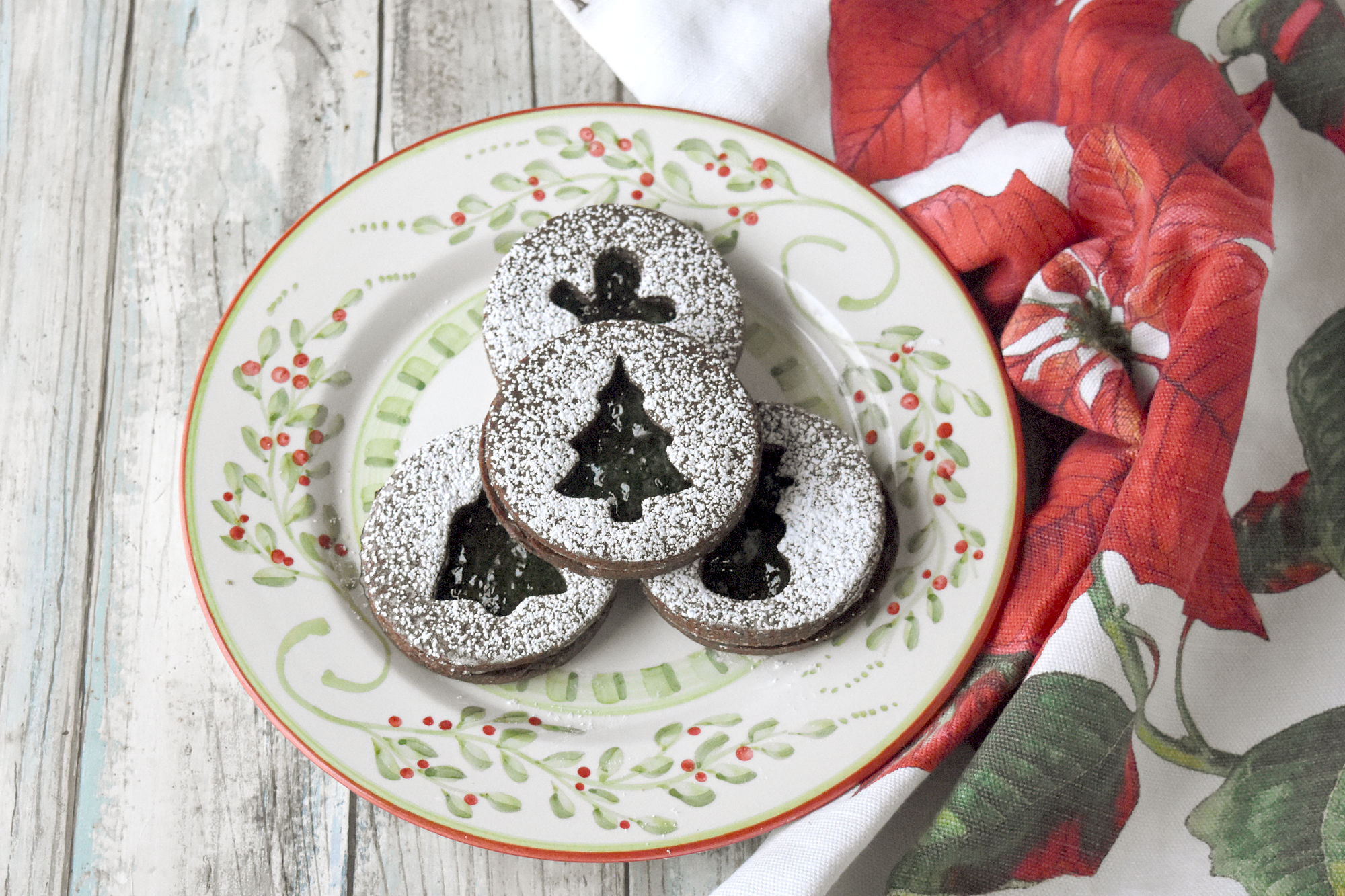 Chocolate Mint Linzer Cookies have a slightly sweet, chocolate shortbread like cookie filled with mint jelly.  Yes.  Mint jelly.  It’s a unique and delicious cookie for the holidays. #ChristmasCookies #linzercookies #mintjelly #chocolatemintcookies #cutoutcookies