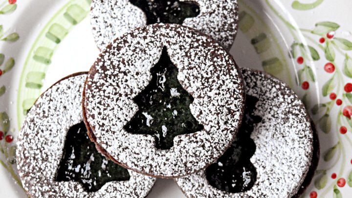 Chocolate Mint Linzer Cookies have a slightly sweet, chocolate shortbread like cookie filled with mint jelly. Yes. Mint jelly. It’s a unique and delicious cookie for the holidays. #ChristmasCookies #linzercookies #mintjelly #chocolatemintcookies #cutoutcookies