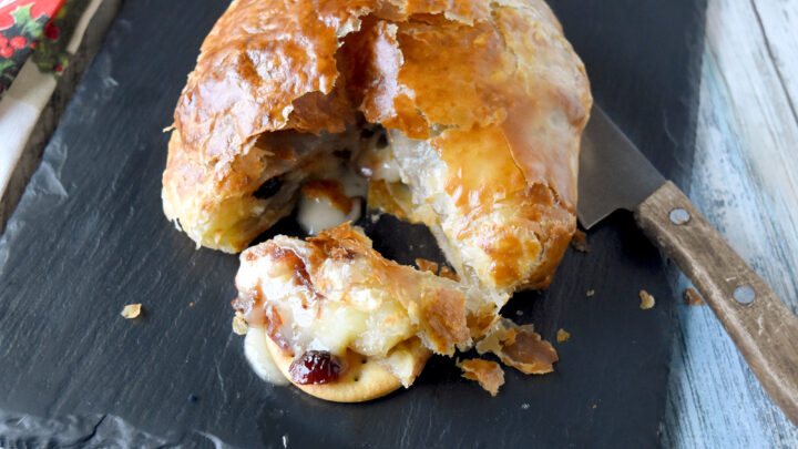 Holiday Baked Brie is a classic Brie en Croûte, or brie baked in puff pastry. I topped the Brie with a simple cranberry sauce made from dried cranberries. #CranberryWeek #bakedbrie #easyappetizer #cranberrysauce