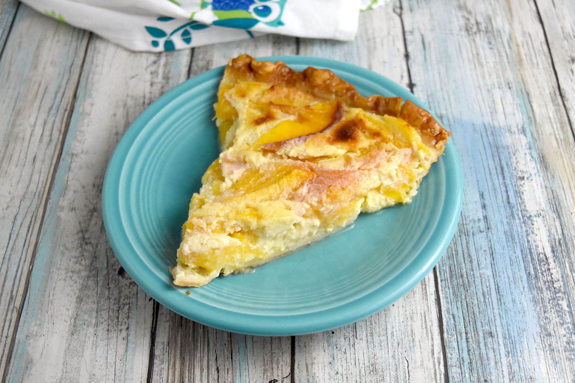 Fresh Peach Custard Pie has summer sweet peaches surrounded by a creamy sweet custard filling. The ingredients are simple but combine to make an irresistible pie your family will love. #custardpie #freshpeaches #inseasonpeaches #OhSayCanYouEB #sponsored #onlyfeedmeEB #madewithEB @egglandsbest
