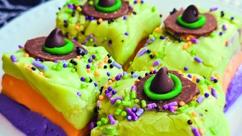 Layers of colorful green, orange, and purple fudge topped with sprinkles and mini witch hats make this easy no-bake treat a spooky party favorite.