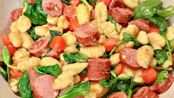 This one-pan gnocchi and sausage recipe, with tomatoes and spinach, is perfect for potlucks, barbecues, and sharing with a hungry crowd!