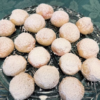 Tender cream cheese cookie surrounding a cherry and sprinkled with powdered sugar. A perfect addition to your Christmas Cookie tray.
