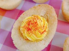 Deviled egg sugar cookies made in egg-shaped molds, topped with yellow frosting and red sanding sugar for an easy cookie recipe perfect for parties.