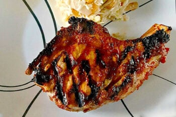 Savor the sweet and smoky harmony of pineapple barbeque chops paired with creamy colada slaw made with coconut chips and macadamia nuts. This dish brings people together and turns any meal into a mini celebration. #bbq #porkchop #pineapplesauce #pineapplebarbecue #PineappleBarbequeChops #ColadaSlaw #BBQlovers #SummerGrilling #TropicalFlavors