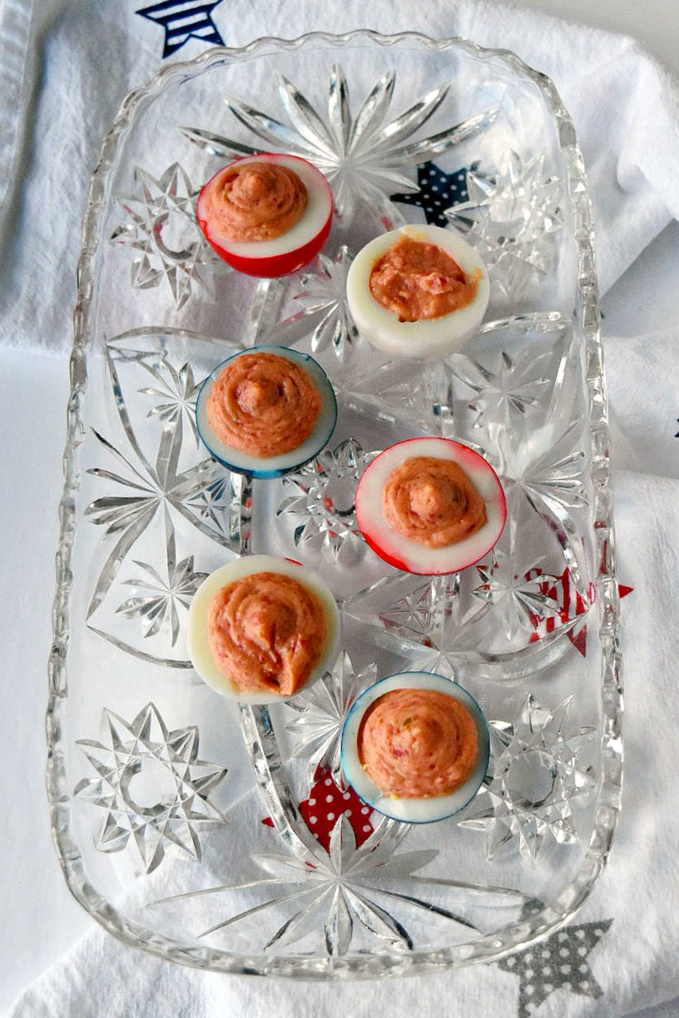 Wow the crowd with Red White & Blue Deviled Eggs, featuring a uniquely tangy roasted beet filling that sets these apart from the rest. Perfect for any patriotic celebration or family event. #deviledeggs #coloredeggs #patrioticfood #RWBDeviledEggs #PatrioticEats #SummerBBQRecipes #FourthofJulyFoods #FoodieFaves #FourthOfJulyFoodies #DeviledEggHeaven #AmericanTable #USAFeast