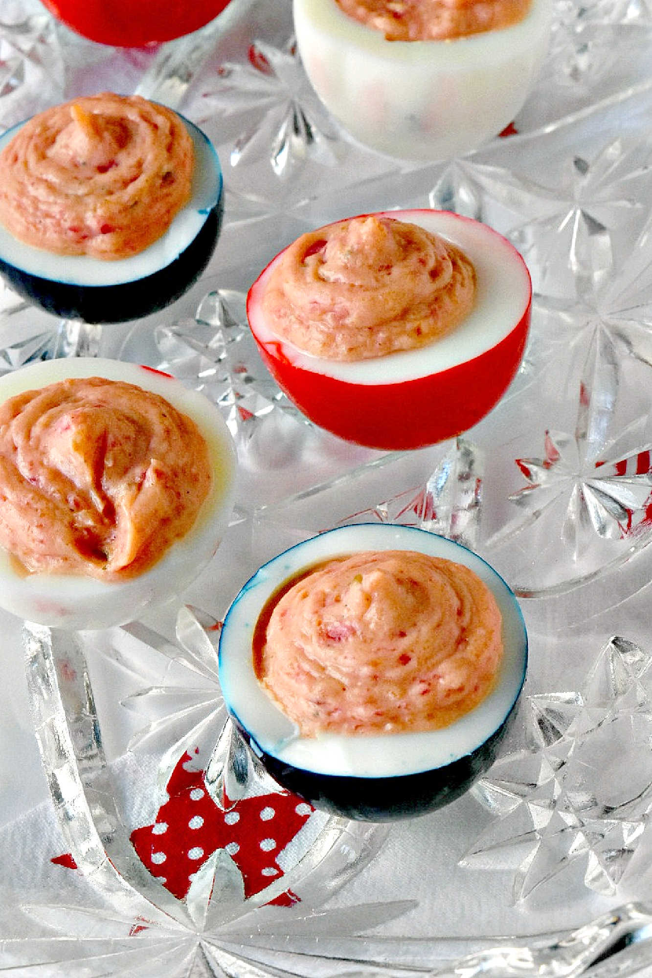 Wow the crowd with Red White & Blue Deviled Eggs, featuring a uniquely tangy roasted beet filling that sets these apart from the rest. Perfect for any patriotic celebration or family event. #deviledeggs #coloredeggs #patrioticfood #RWBDeviledEggs #PatrioticEats #SummerBBQRecipes #FourthofJulyFoods #FoodieFaves #FourthOfJulyFoodies #DeviledEggHeaven #AmericanTable #USAFeast