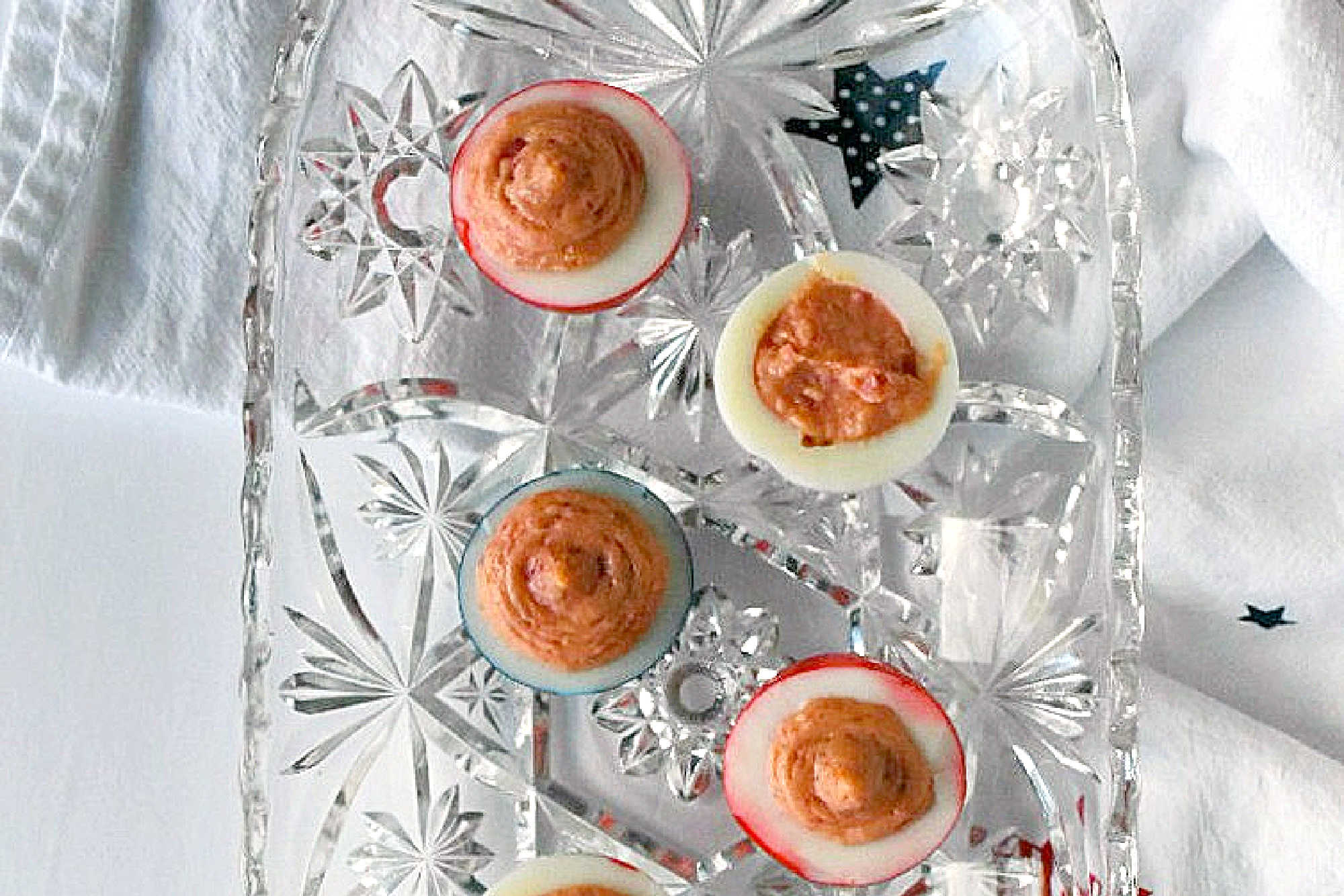 Wow the crowd with Red White & Blue Deviled Eggs, featuring a uniquely tangy roasted beet filling that sets these apart from the rest. Perfect for any patriotic celebration or family event. #deviledeggs #coloredeggs #patrioticfood #RWBDeviledEggs #PatrioticEats #SummerBBQRecipes #FourthofJulyFoods #FoodieFaves #FourthOfJulyFoodies #DeviledEggHeaven #AmericanTable #USAFeast