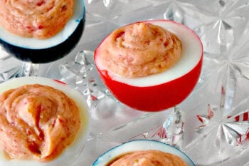 Wow the crowd with Red White & Blue Deviled Eggs, featuring a uniquely tangy roasted beet filling that sets these apart from the rest. Perfect for any patriotic celebration or family event. #deviledeggs #coloredeggs #patrioticfood #RWBDeviledEggs #PatrioticEats #SummerBBQRecipes #FourthofJulyFoods #FoodieFaves #FourthOfJulyFoodies #DeviledEggHeaven #AmericanTable #USAFeast