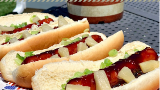 A regular hot dog is pan-fried and coated with a Hawaii-inspired glaze, then garnished with pineapple and onion.