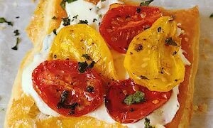 Roasted tomato tarts with lemon basil ricotta feature crisp puff pastry, caramelized tomatoes, and fresh basil for a colorful summer appetizer.