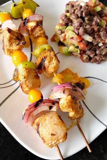 Fire up the grill for Chicken Fajita Kabobs loaded with juicy chicken, sweet peppers, onions, and bursty cherry tomatoes. Serve the smoky skewers with black bean and avocado salsa for a fresh, creamy, colorful Tex-Mex dinner that’s cookout ready and family approved. #ChickenFajitaKabobs #EasyGrillingRecipes #SummerDinner #ChickenKabobs #TexMexRecipes #AvocadoSalsa #FamilyMeals #OurFamilyTable