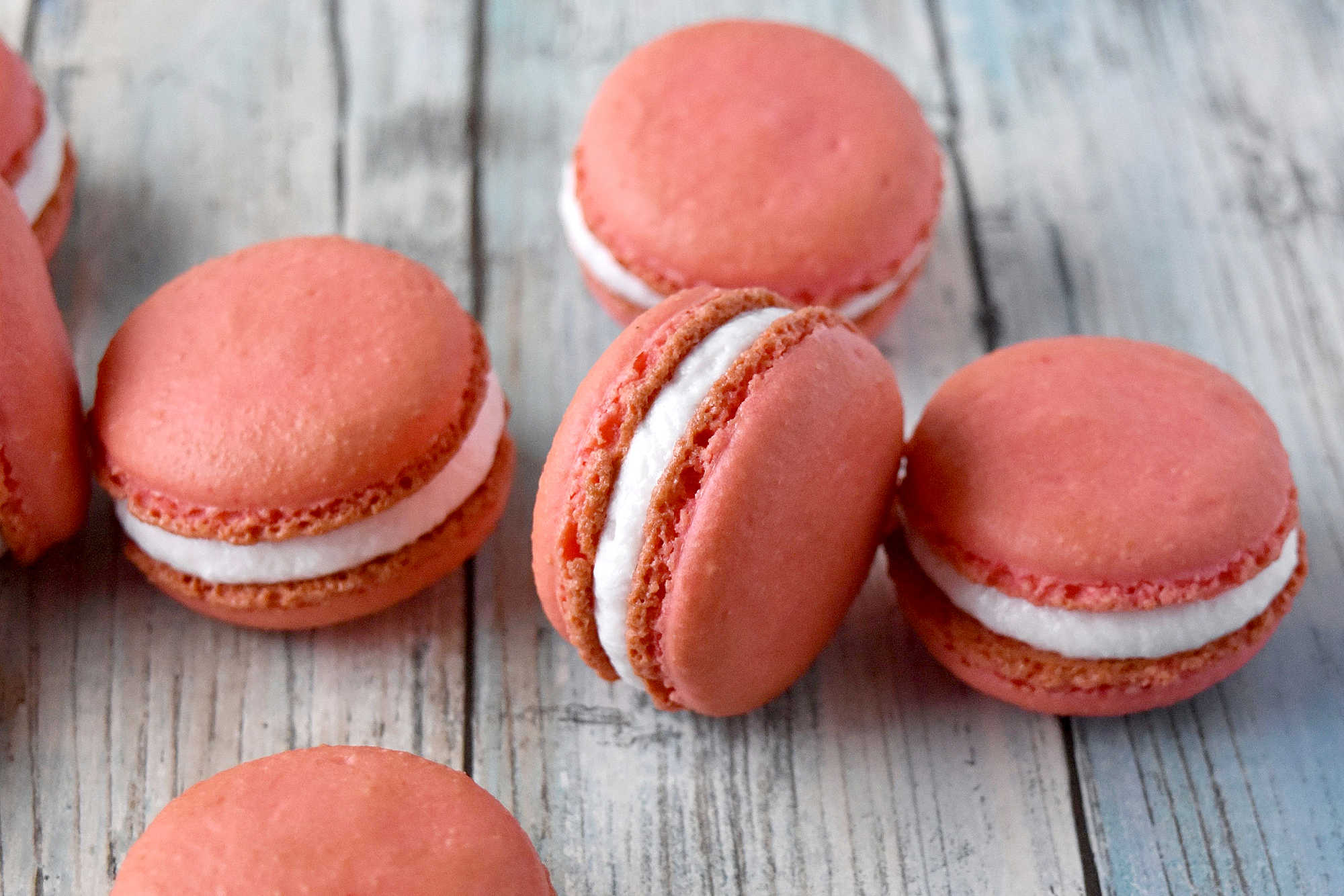 Peach macarons are the sweetest little summer bake. These use freeze-dried peaches in the shells and peach syrup in the filling for bright, fruity flavor in every bite. Perfect for a beginner-friendly showstopper! #peachmacarons #macarons #frenchmacarons #macaronlove #peachdessert #summerdesserts #prettybakes #bakingfromscratch #homebaker #desserttable #teapartyideas #bridalshowerdesserts #Stonefruit